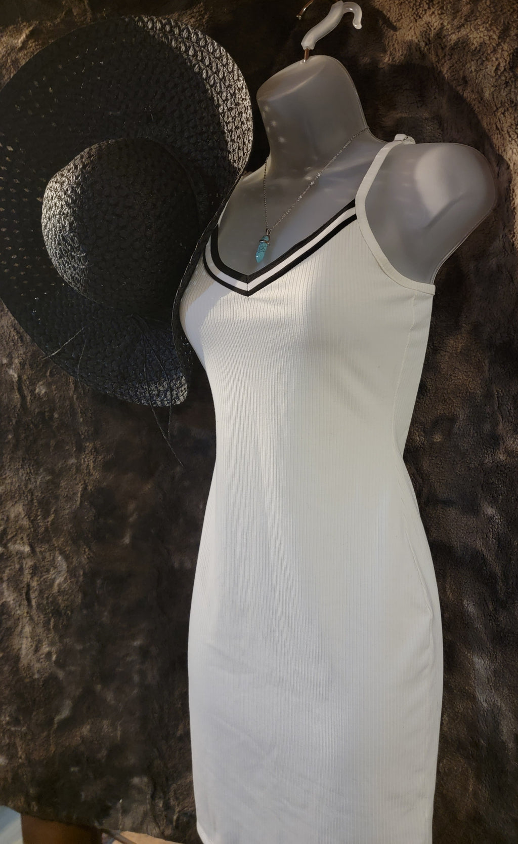 Small white sundress with black trim,  black straw sun hat and a light blue crystal necklace.