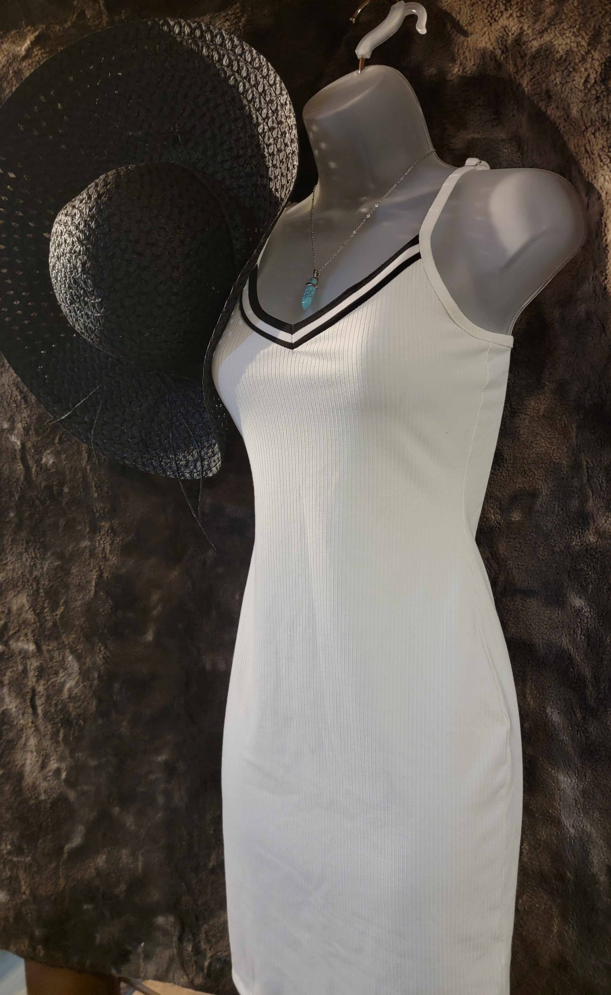 Small white sundress with black trim,  black straw sun hat and a light blue crystal necklace.